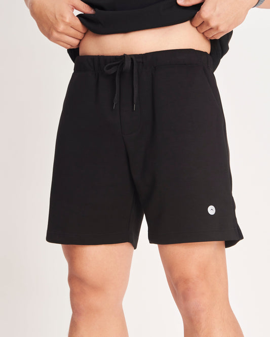 Person wearing black shorts on a plain background