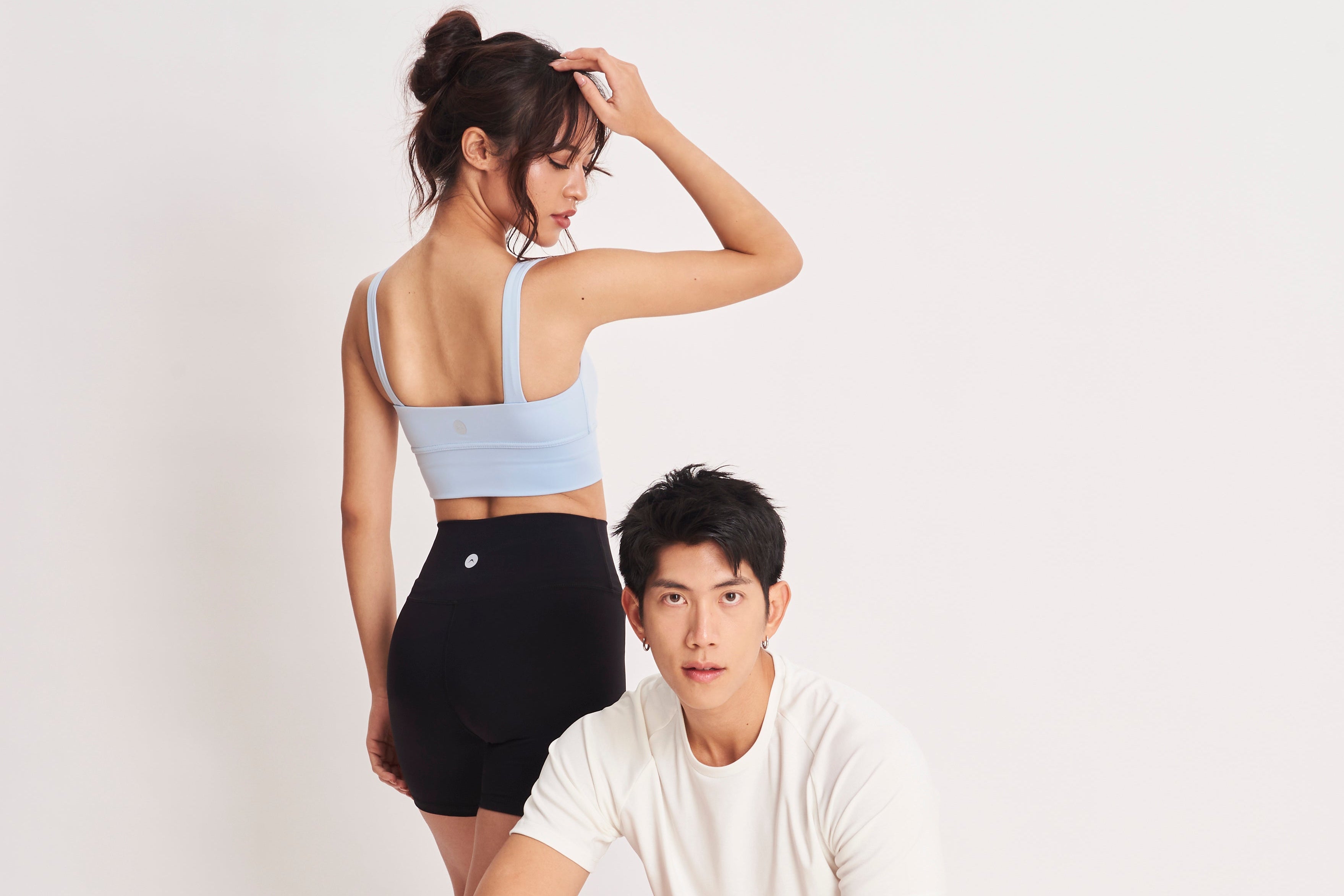 Two people in athletic wear posing against a white background