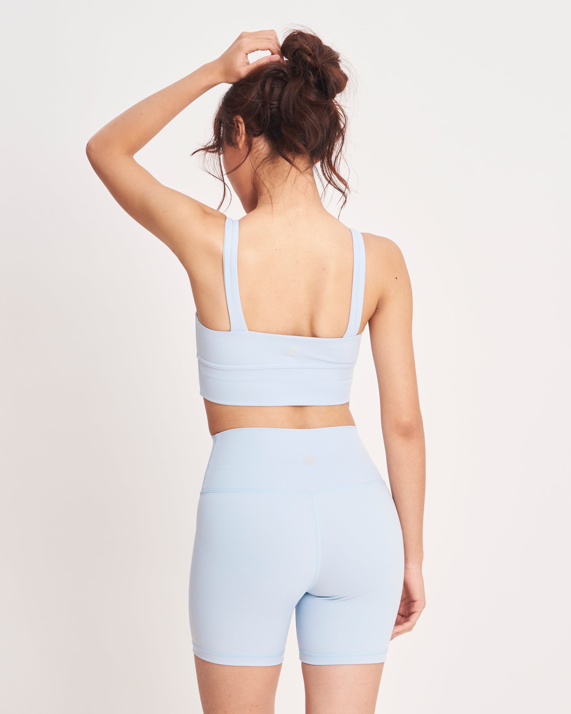 Person wearing a light blue sports bra and shorts set on a white background